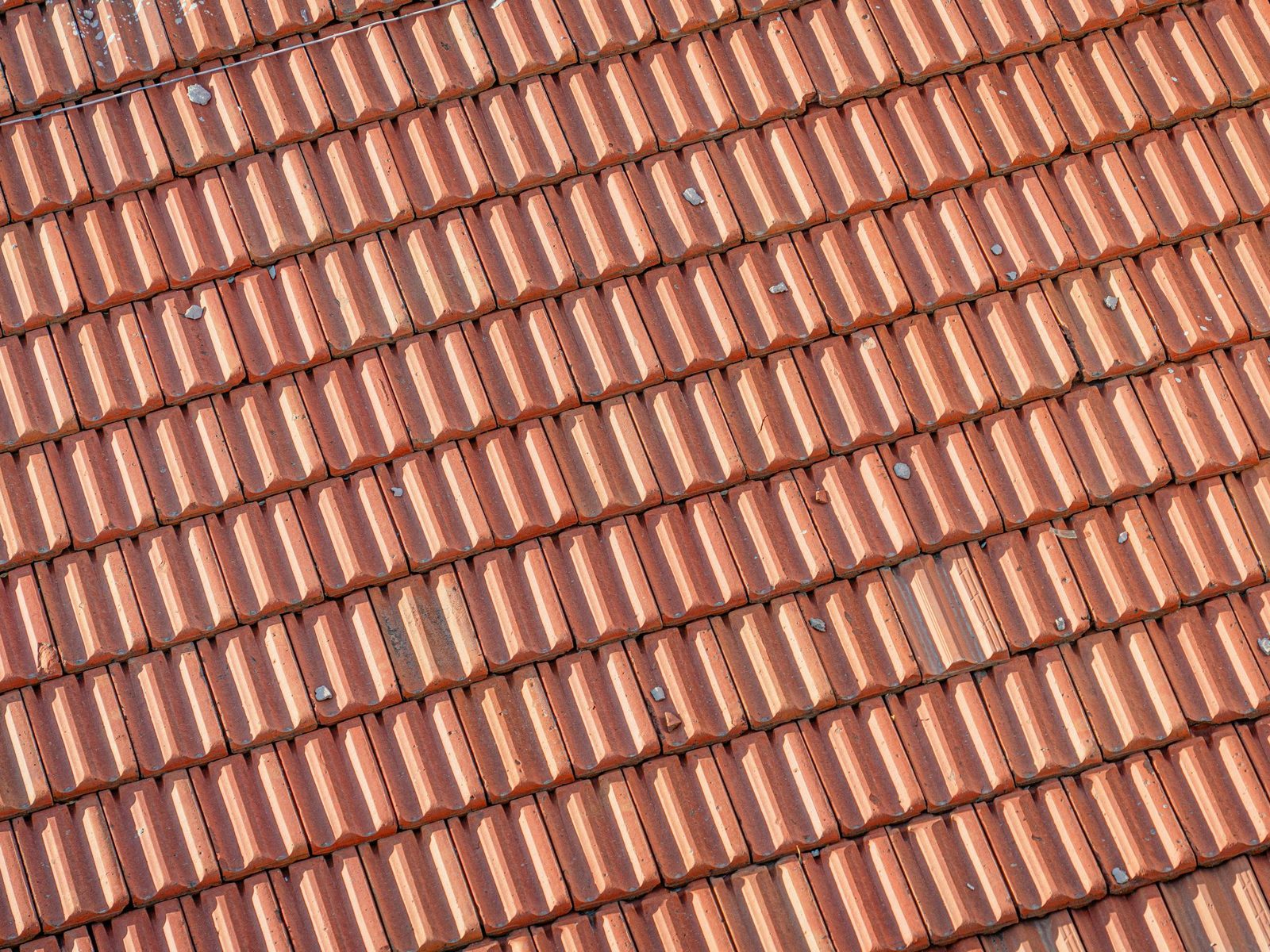 Close view of red clay roof tiles with small stones on them